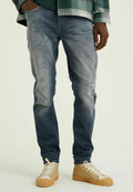 Ausgebleichte blaue Jeans mit distressed Details, schmaler Schnitt und leichter Waschung. Kombiniert mit tanfarbenen High-Top-Sneakern mit strukturiertem Sohlen.
