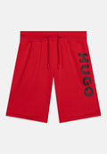 Rote knielange Shorts mit elastischem Bund und Kordelzügen, mit großen schwarzen "HUGO"-Schriftzügen vertikal am rechten Bein.