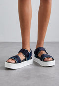 Marineblaue Sandalen mit Velcro-Riemen und weiß gesprenkelten Sohlen. Offenes Toe-Design mit kontrastierenden dunklen Details und Markenakzenten.