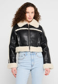 Schwarze Lederjacke mit kurzem Schnitt und Schafslederkragen und -manschetten, ausgestattet mit einem Reißverschluss vorne und breiten horizontalen Streifen. Die Jeans aus Denim vervollständigen das Outfit.