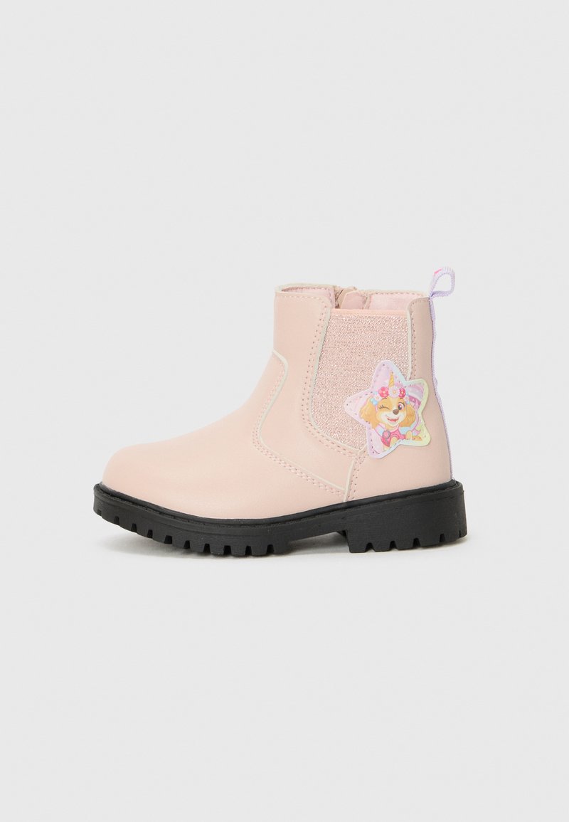 Rosa Knöchelstiefel mit schwarzem Sohle, ausgestattet mit einem glänzenden Seitenpaneel und einem Badge mit einer cartoonhaften Figur in Sternform auf der Außenseite.