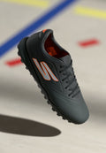 Schwarzer Sportschuh mit glatter, matter Oberfläche, ausgestattet mit orangefarbenen Akzenten und einer strukturierten Sohle für besseren Halt. Schnürsenkel und Belüftungsdetails sind enthalten.