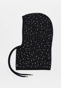 Schwarze gestrickte Kapuze mit weißen Punkten und zwei Kordelzügen mit silbernen Metallenden, flach liegend auf weißem Hintergrund.