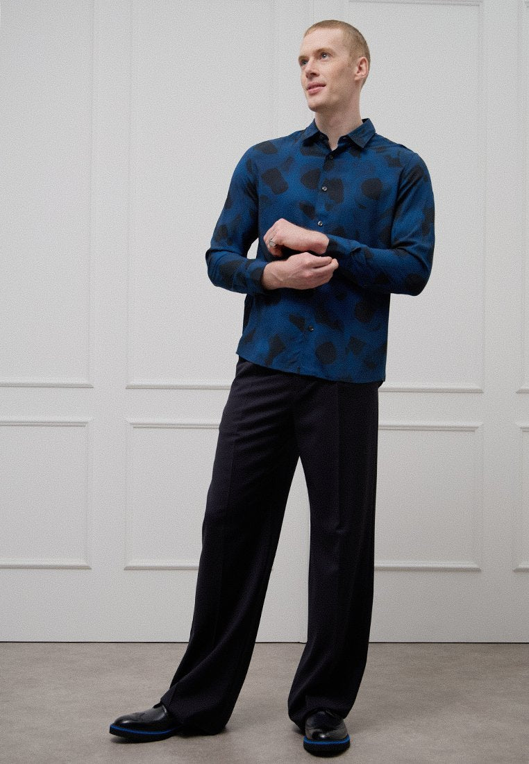 Blaues Hemd mit langen Ärmeln und schwarzem abstraktem Muster, kombiniert mit dunkler Hose. Glatter Stoff, Kentkragen mit Knöpfen und tailliertes Design.