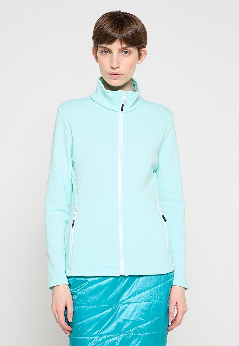 Hellblaue Jacke mit Reißverschluss aus weichem Stoff, mit hohem Kragen und Reißverschlusstaschen, kombiniert mit einem strukturierten türkisfarbenen Rock.