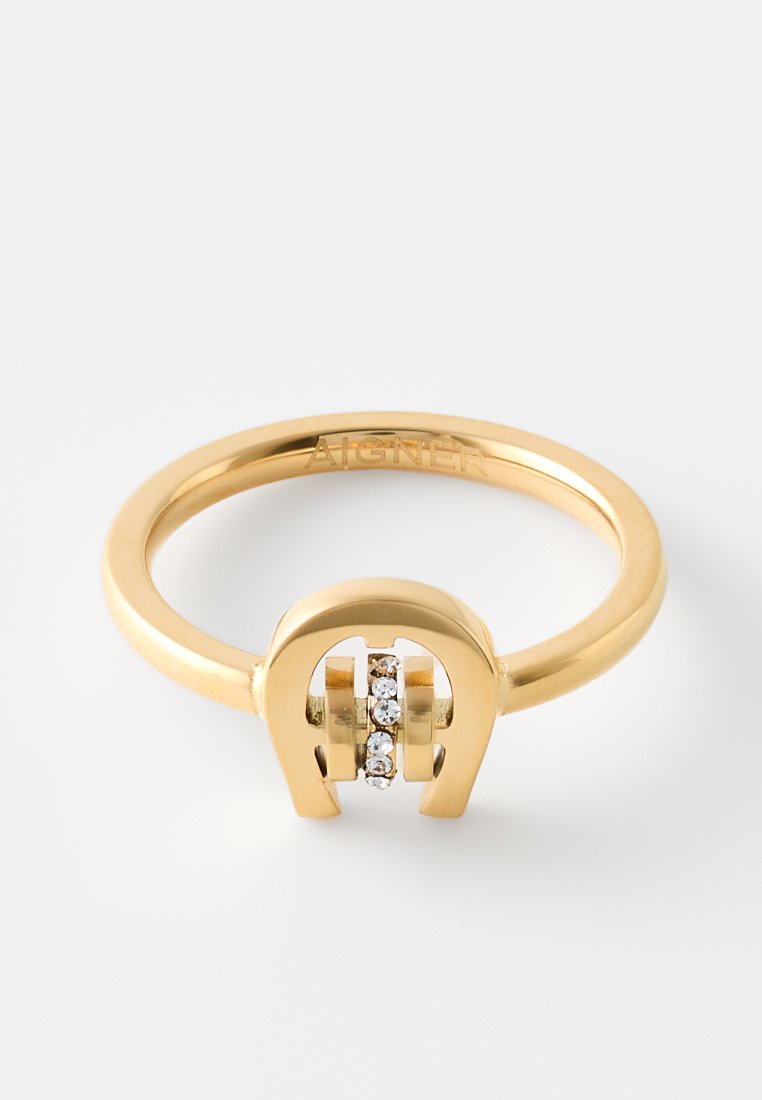 Goldring mit hufeisenförmigem Design, der eine vertikale Reihe kleiner klarer Edelsteine auf einem schlichten weißen Hintergrund hält.