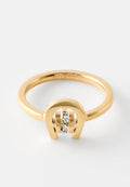 Goldring mit hufeisenförmigem Design, der eine vertikale Reihe kleiner klarer Edelsteine auf einem schlichten weißen Hintergrund hält.