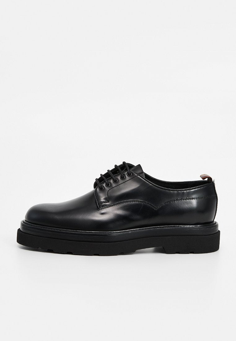 Schwarze, geschnürte Lederschuhe mit glatter Oberfläche, dicker schwarzer Sohle und dezenten Steppnähten entlang des Schaftes.