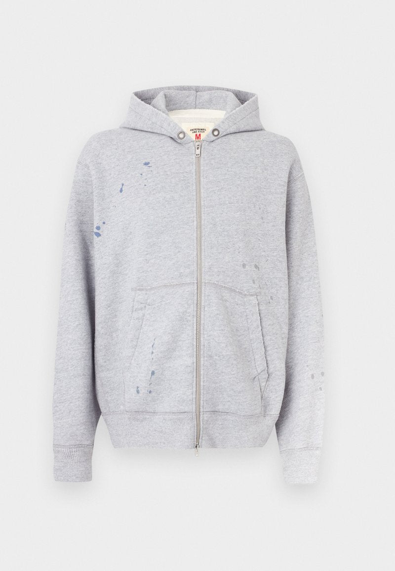 Grauer Kapuzenpullover mit Reißverschluss, aus Baumwollmischung, mit Kapuze, Fronttaschen und Farbspritzern auf der linken Seite.
