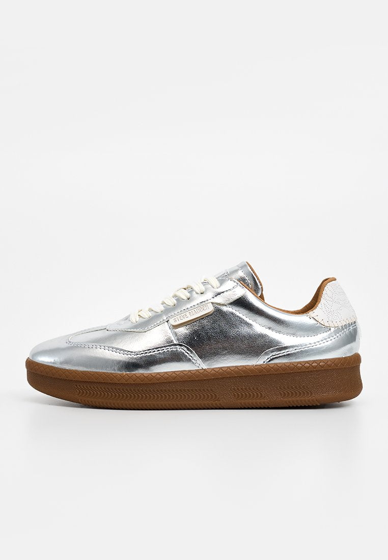 Silberne metallische Sneaker mit weißen Akzenten, mit einem Schnürdesign und einer strukturierten braunen Gummisohle. Markenlabel an der Seite sichtbar.