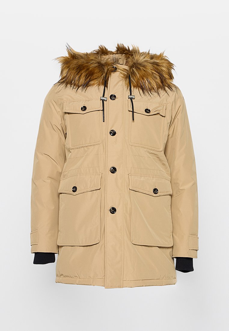Beige Winterparka mit Kapuze aus Kunstfell, Knopf- und Reißverschluss, vier aufgesetzten Fronttaschen und gerippten schwarzen Bündchen.