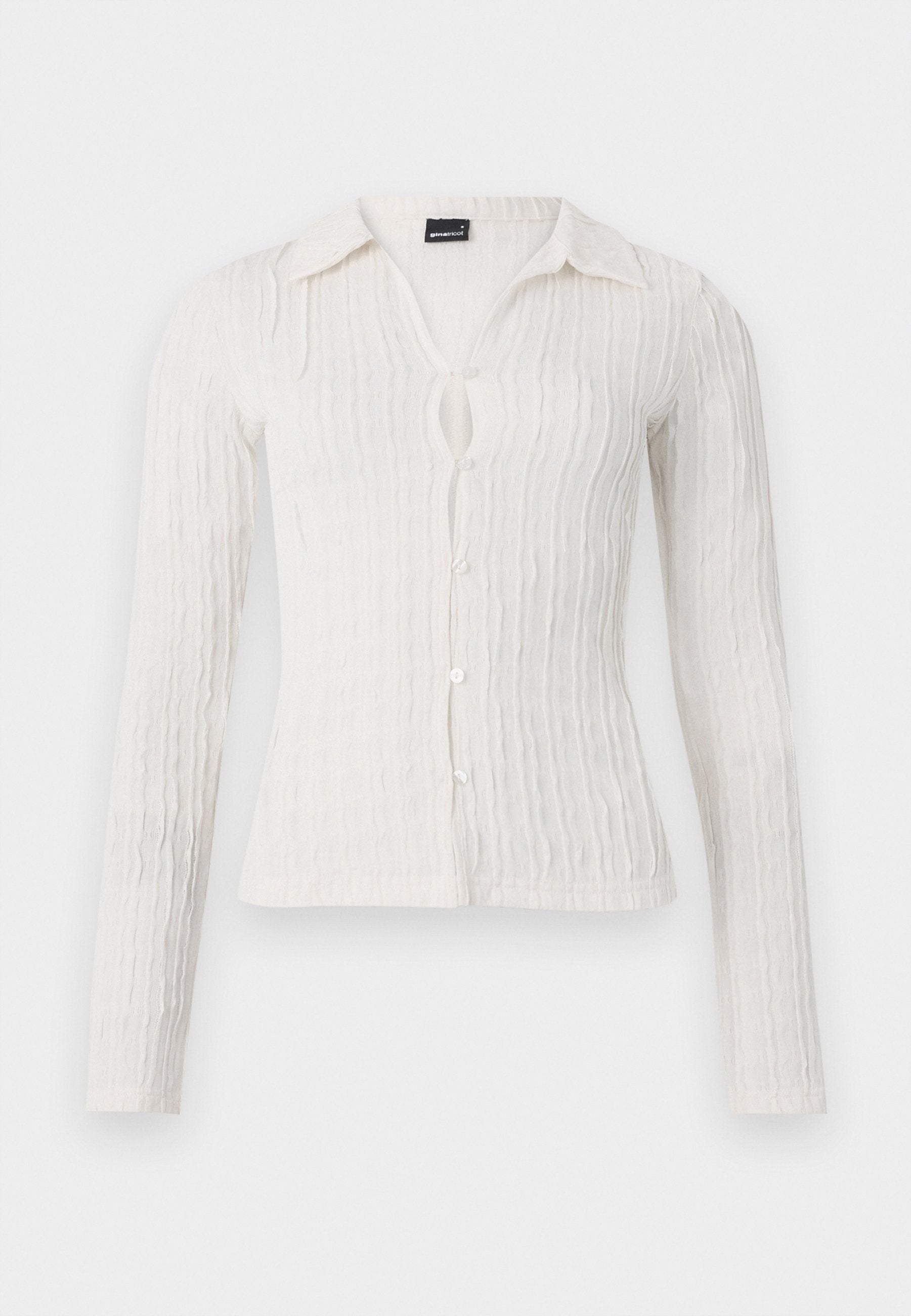 Langärmelige weiße Bluse mit strukturiertem Rippdesign, kragenloser Halslinie, Knopfverschluss und einer kleinen Schlitzöffnung an der Vorderseite.