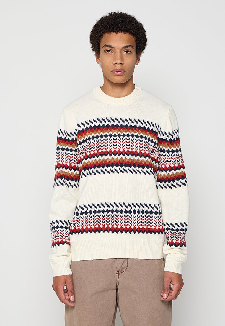 Cremfarbener Strickpullover mit geometrischen Mustern in Rot, Marineblau und Braun, mit Rundhalsausschnitt und langen Ärmeln.