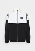 Schwarze, weiße und graue Windbreaker-Jacke mit hohem Kragen, Reißverschluss vorne, elastischen Bündchen und horizontalem Farbschema. Logo-Detail auf der Vorderseite.