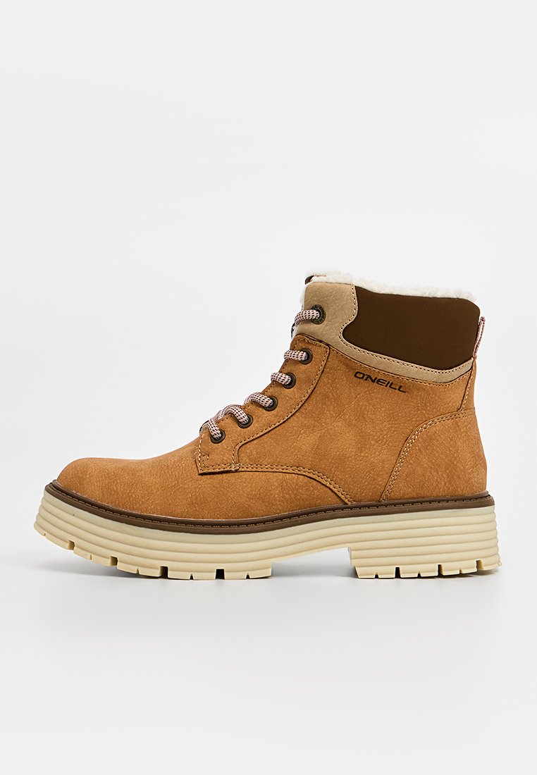 Braune Wildleder-Ankle-Boots mit rundem Zehenbereich, beigem Besatz, Kunstfellfutter und weißer Gummisohle. Mit Metallösen und Schnürsenkeln ausgestattet. Branding an der Seite.