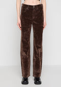 Braune Samt-Hose mit geradem Bein, Fronttaschen und Knopfverschluss, getragen mit schwarzen Lederschuhen und einem bauchfreien Oberteil.