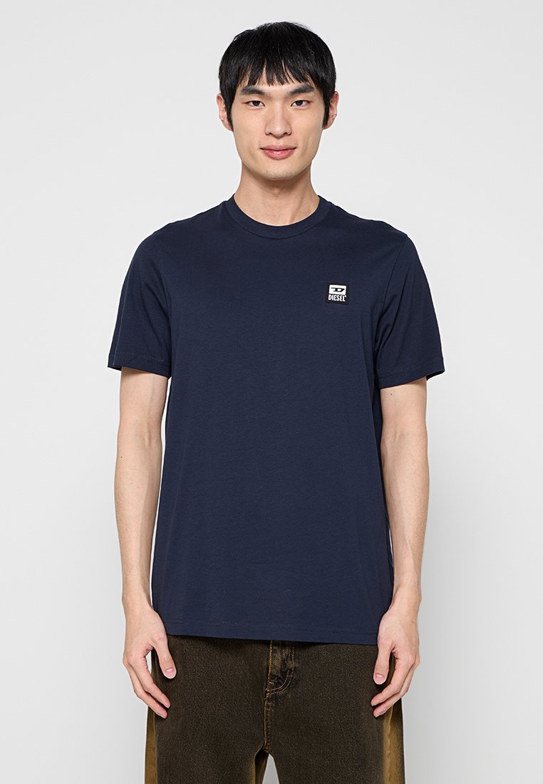 Marineblaue Baumwoll-T-Shirts mit Rundhalsausschnitt und kurzen Ärmeln. Verfügt über ein kleines rechteckiges weißes Etikett mit dem "DIESEL"-Logo auf der Brust.