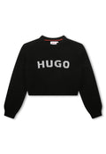 Schwarzer gestrickter kurzer Pullover mit gerippter Textur, der das Wort "HUGO" deutlich in Weiß über der Brust trägt. Runder Halsausschnitt.