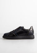 Schwarze Ledersneaker mit strukturierten Einsätzen, glatten Akzenten, blauen Nähten und einer durchgehend schwarzen Sohle. Gerundete Zehenform.