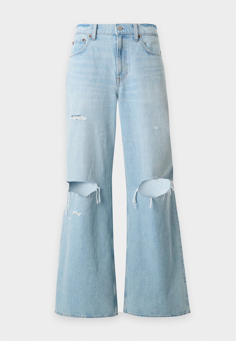 Hellblaue Jeans mit weitem Bein, hoher Taille und abgenutzten Rissen an beiden Knien sowie einem kleinen Riss am linken Oberschenkel.
