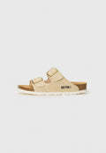 Beige Slippers mit zwei verstellbaren Riemen, goldfarbenen Schnallen und Korksohle. Verfügt über eine strukturierte Außensohle und den Markennamen seitlich aufgedruckt.