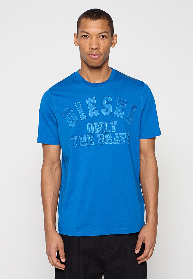 Blaues Baumwoll-T-Shirt mit dem Aufdruck "DIESEL ONLY THE BRAVE" in kontrastierenden Farben. Kurze Ärmel, Rundhalsausschnitt und glatte Textur.