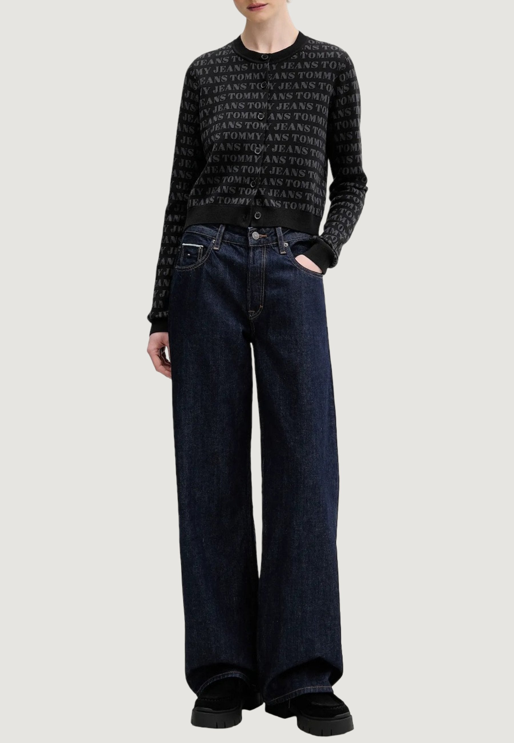 Schwarzer Pullover mit wiederholtem Textmuster, kombiniert mit hoch taillierter, weit geschnittener dunkler Denim-Jeans. Das Outfit besticht durch ein lässiges Design und eine entspannte Passform.