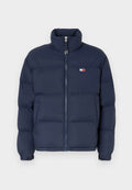 Marineblaue Steppjacke mit hohem Kragen, Reißverschluss und horizontalem Steppmuster. Mit einem kleinen Logo-Patch in Rot, Weiß und Blau.