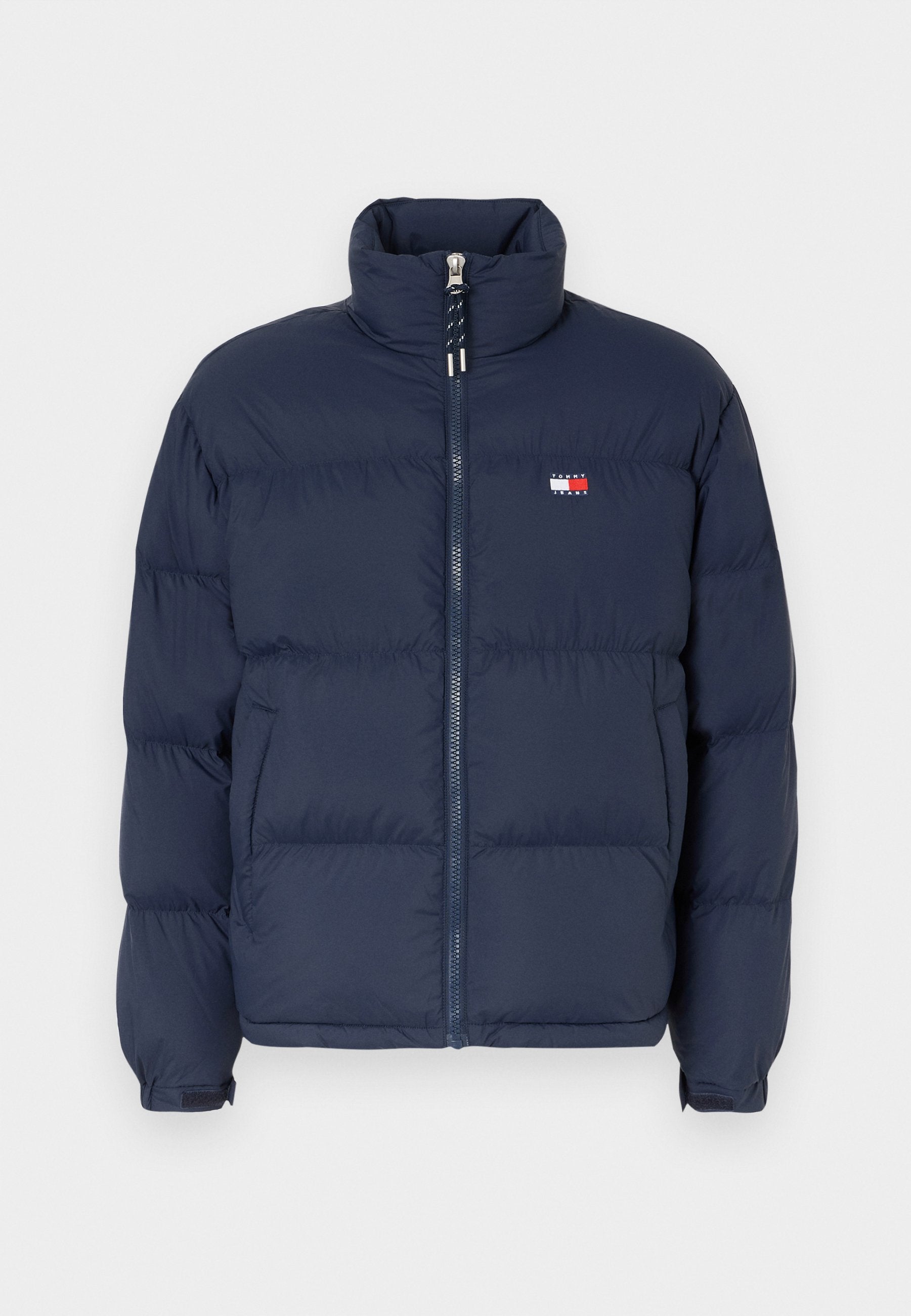 Marineblaue Steppjacke mit hohem Kragen, Reißverschluss und horizontalem Steppmuster. Mit einem kleinen Logo-Patch in Rot, Weiß und Blau.