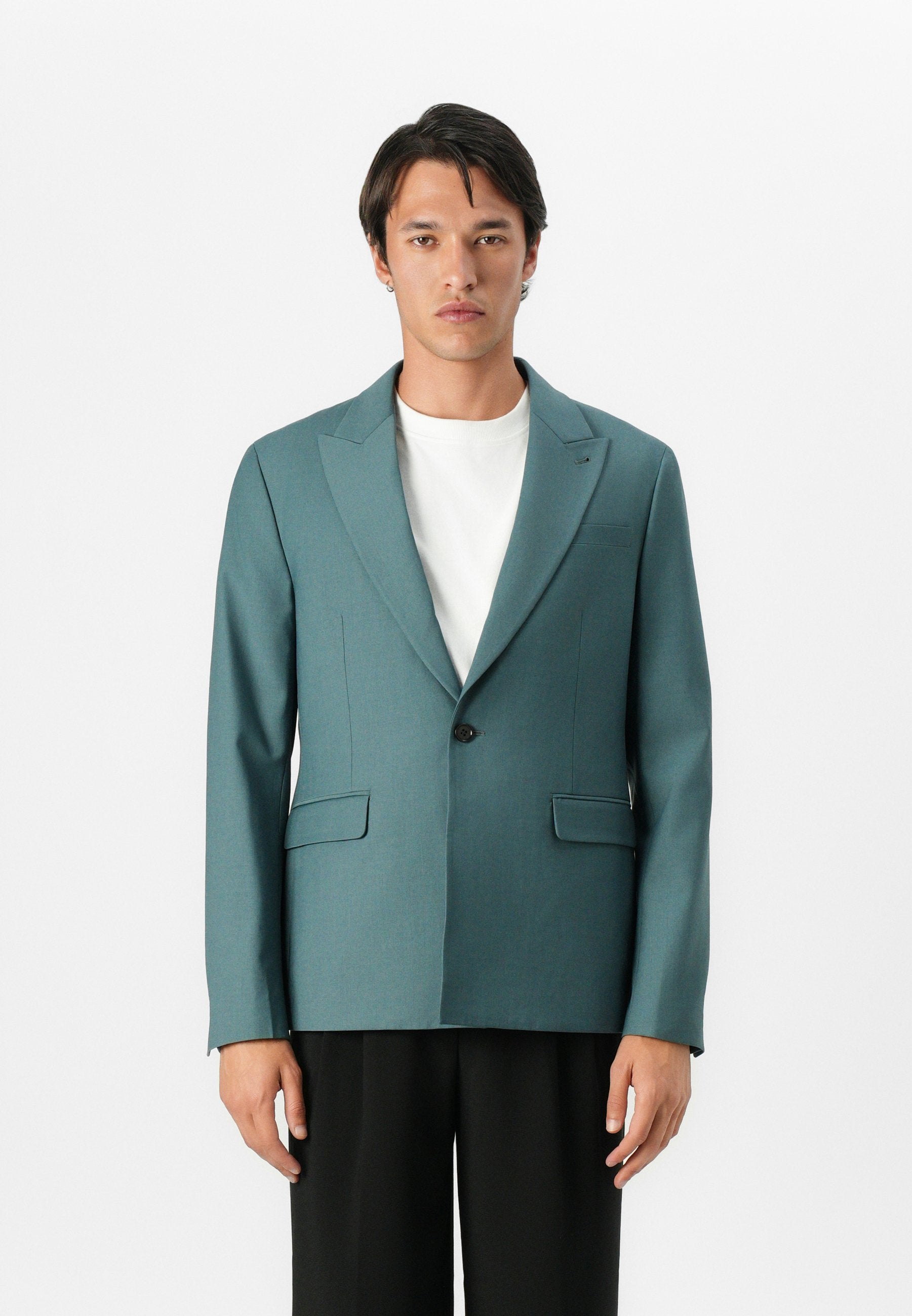 Türkiser Blazer mit Reverskragen, Ein-Knopf-Verschluss, zwei vorderen Taschen und taillierter Passform, kombiniert mit einem weißen Hemd und schwarzen Hosen.
