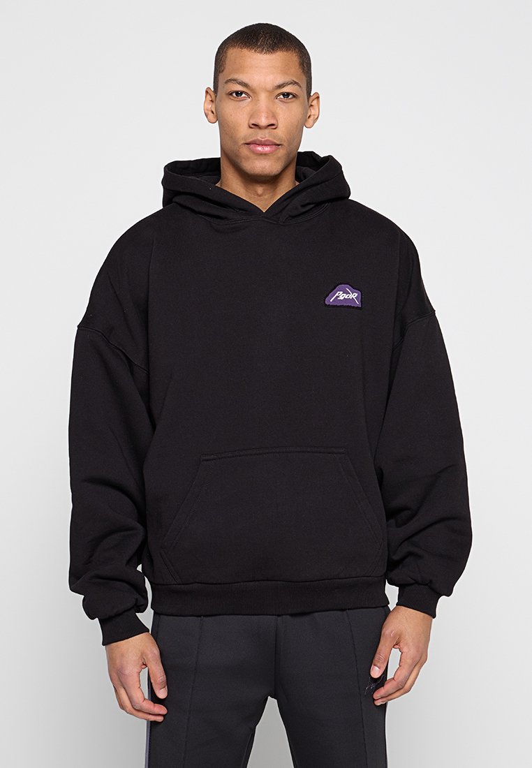 Schwarzer Hoodie aus Baumwolle mit einer Kängurutasche, gerippten Bündchen und einem kleinen lila Logo auf der Brust. Einfaches Design mit lockerem Sitz.