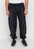 Schwarze Jogginghose mit weißen römischen Ziffern "XL" am linken Bein und "VI" am rechten Bein, getragen mit schwarz-weißen Sneakers und einem weißen Hemd.