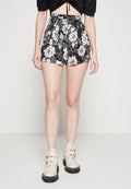 Schwarze Blumenbermuda mit weißen Blumen, hoch tailliertes Design, mit einem strukturierten Taillenbund. Kombiniert mit cremförmigen Knöchelstiefeln mit Schnallen.