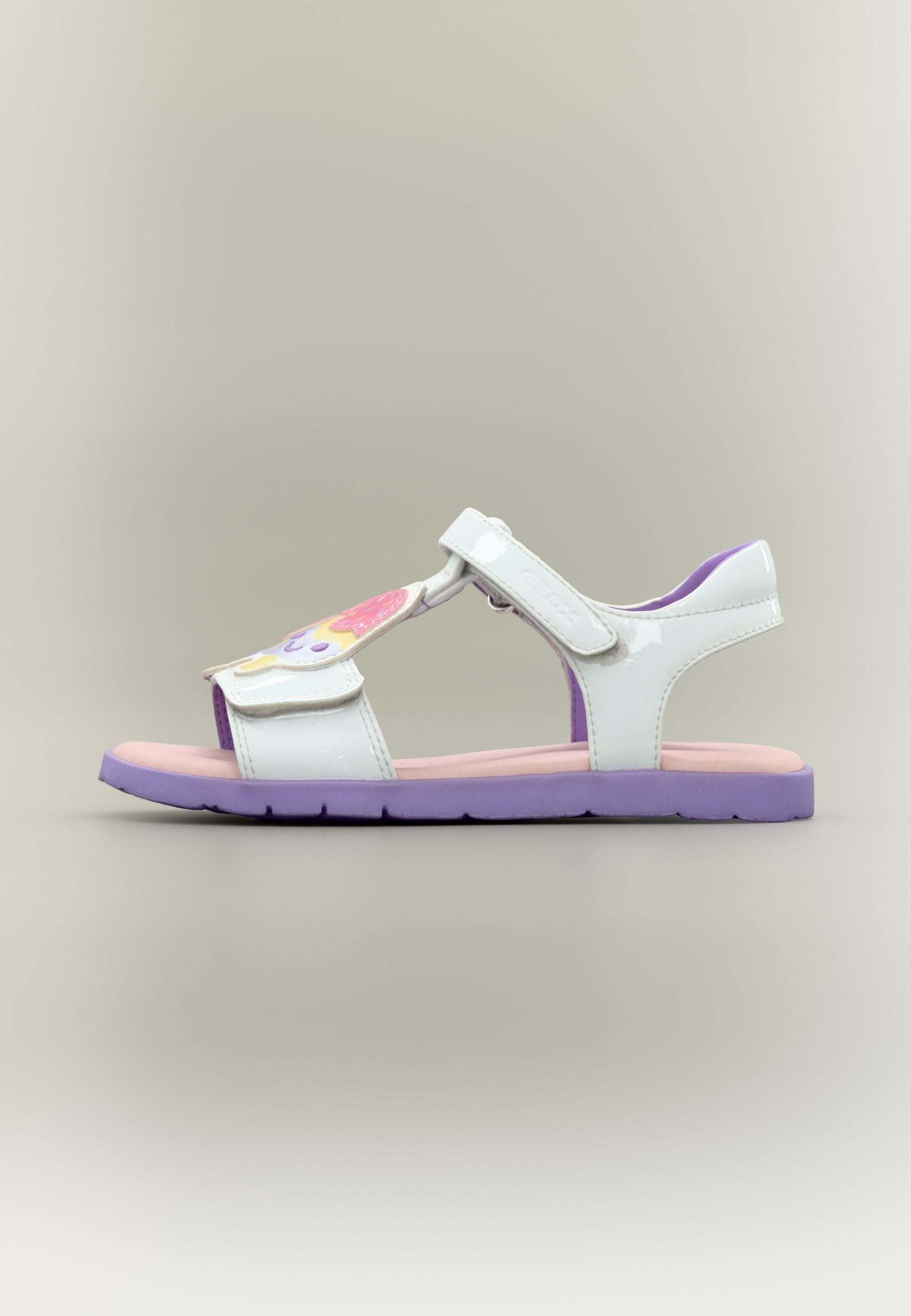 Weiße Sandalen mit einem Klettverschluss und einem bunten Eiscreme-Design auf der Vorderseite, mit einer rosa Innensohle und einer lila Laufsohle.
