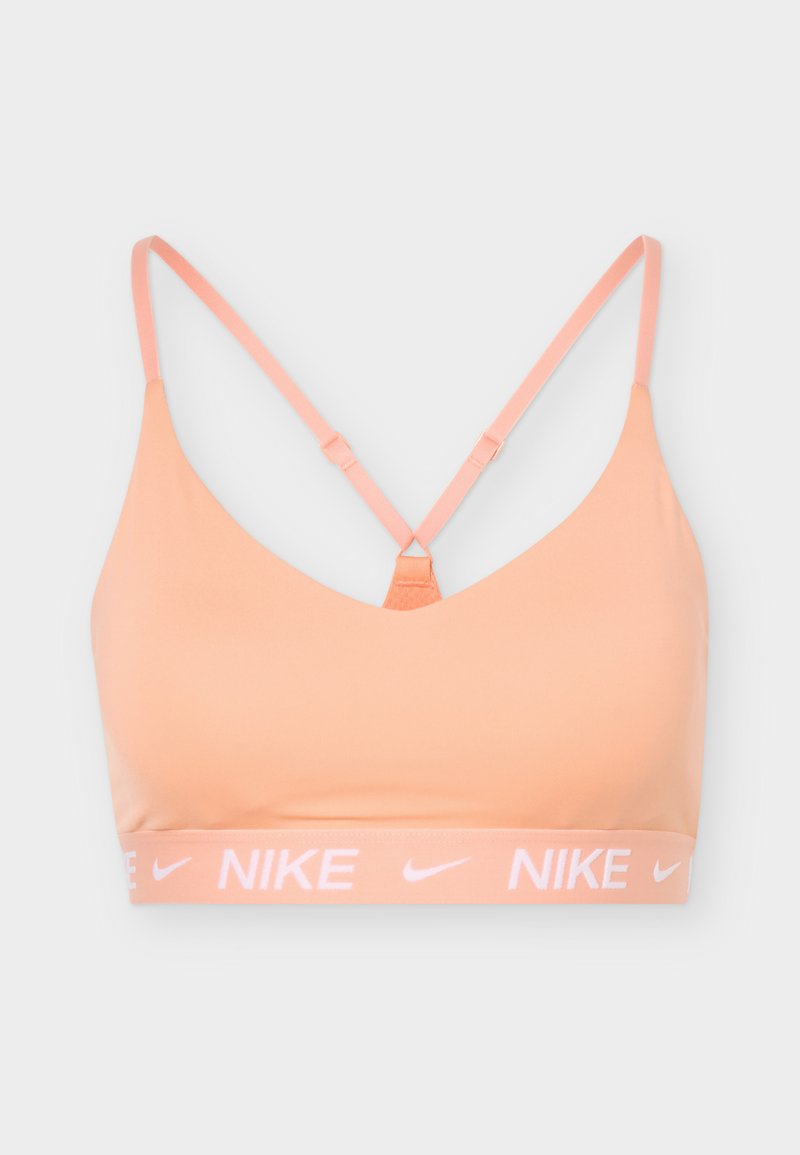 Hellpfirsichfarbener Sport-BH mit dünnen, verstellbaren Trägern und elastischem Band mit wiederholtem Nike-Logo und Swoosh in Weiß.
