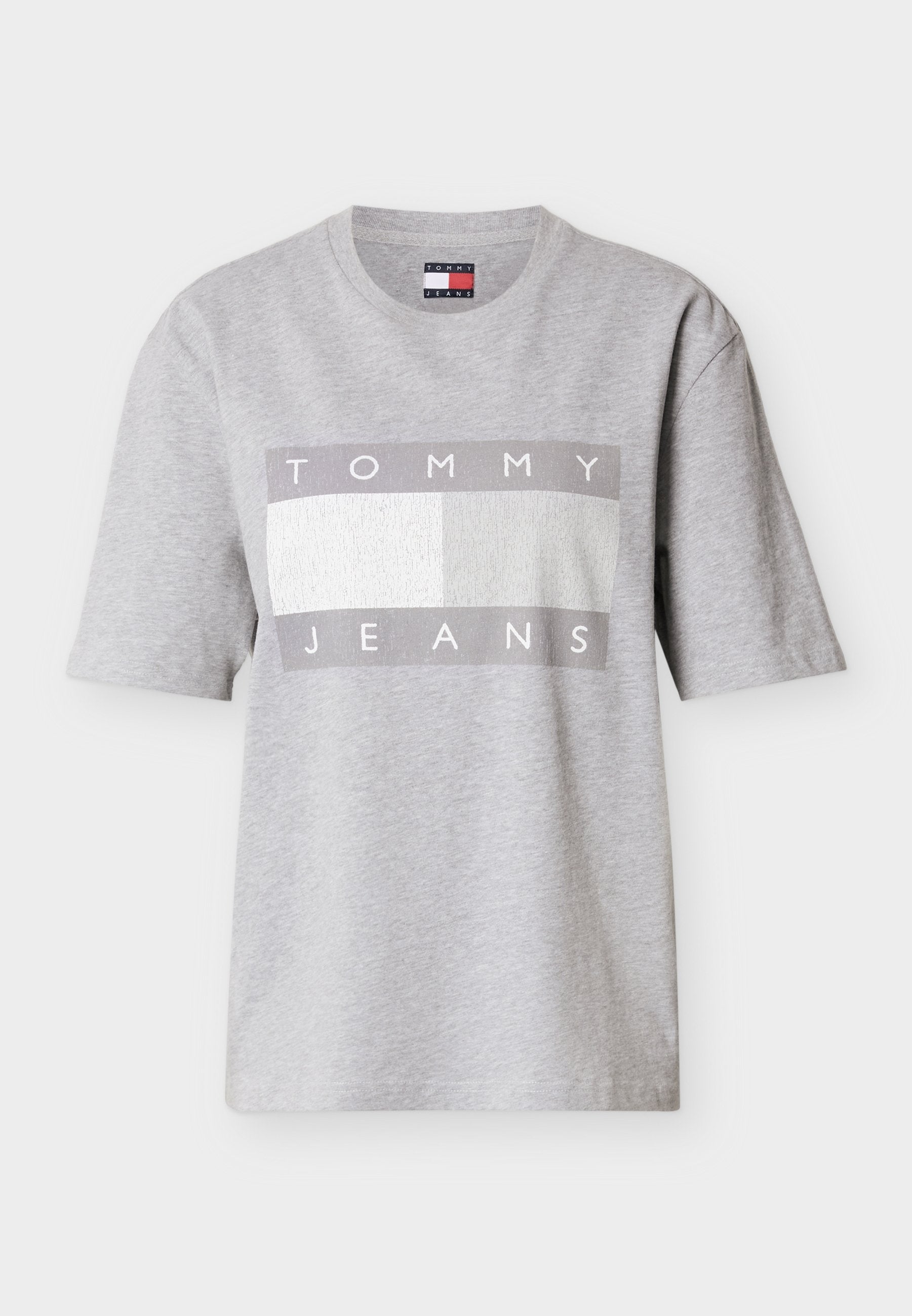 Graues T-Shirt mit kurzen Ärmeln aus Baumwolle, mit einem rechteckigen Motiv, das "TOMMY" in Weiß und "JEANS" in Grau auf einem strukturierten Hintergrund zeigt.