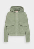 Grüne Cord-Jacke mit Kapuze, vorderem Reißverschluss, zwei großen Fronttaschen und elastischen Bündchen am Saum und an den Ärmeln für eine taillierte Passform.