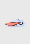 Fußballschuh mit orangefarbener texturierter Vorderseite, weißem gestricktem Kragen, braunen und schwarzen Akzenten sowie orangefarbenen Stollen auf einer weißen Sohle vor grauem Hintergrund.