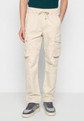 Beige Cargo-Hosen mit einem Kordelzugbund, mehreren seitlichen Taschen und glatter Textur; getragen mit grau-weißen Sneakers.