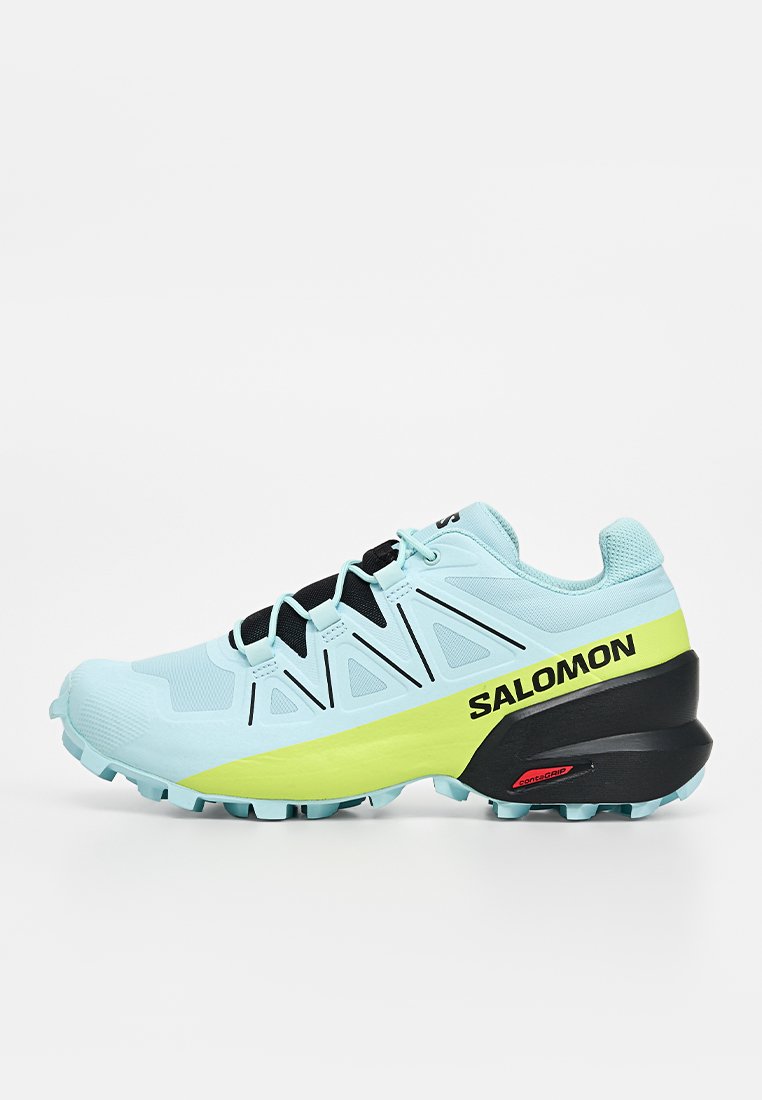 Hellblaue und gelbe Salomon Trailrunning-Schuhe mit schwarzer Sohle und Logo, entworfen für raues Gelände im Freien.