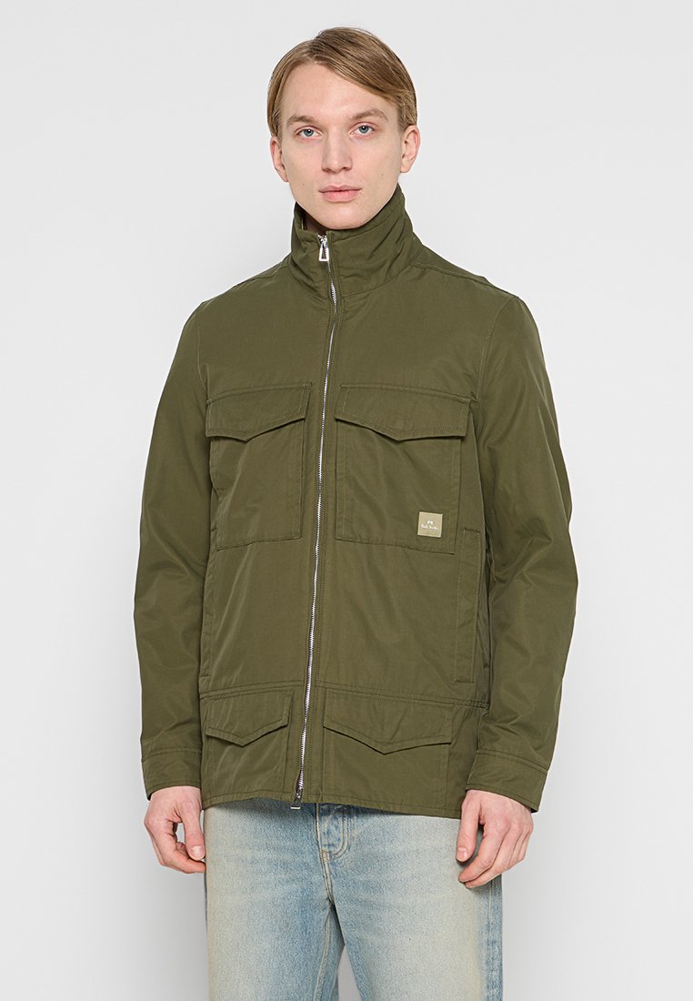 Olivgrüne Jacke mit hohem Kragen, Reißverschluss und zwei Brusttaschen. Aus glattem Stoff gefertigt; verfügt über einen kleinen Logopatch.