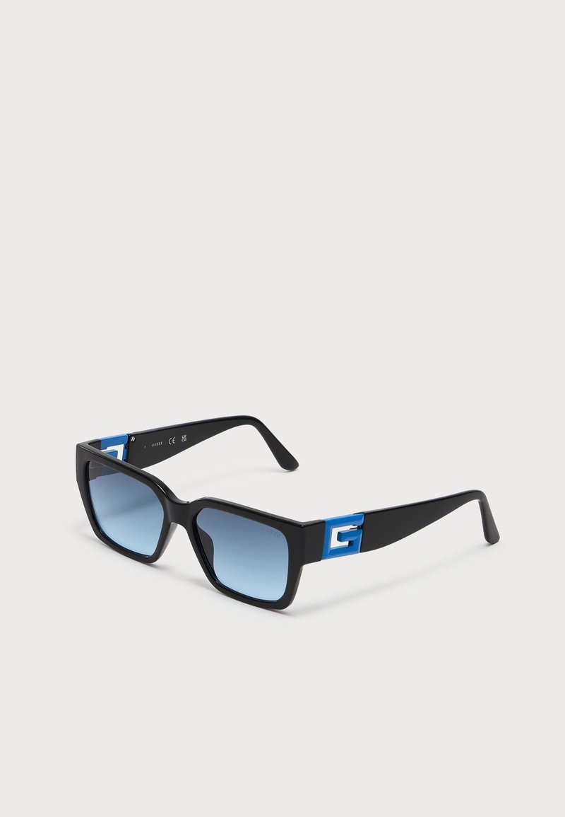 Schwarze rechteckige Sonnenbrille mit blauen Verlaufsgläsern und blauen dekorativen Akzenten an den Bügeln, dargestellt auf weißem Hintergrund.
