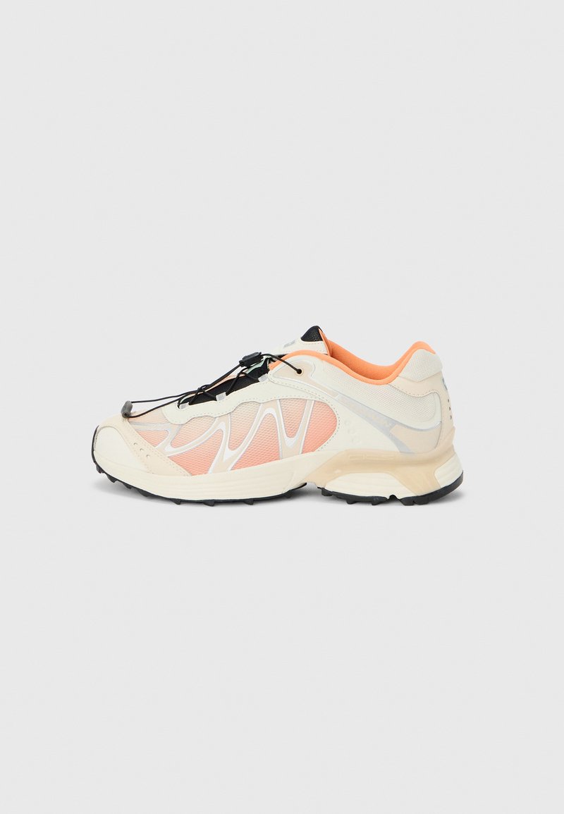 Sneaker mit einem hellcremefarbenen und pastellrosa Mesh-Obermaterial, schwarzen Akzenten, elastischen Schnürsenkeln und einer strukturierten schwarzen Gummisohle.