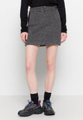 Schwarzer und weißer gemusterter Denim-Rock mit hoher Taille, vorderen Knöpfen und leichtem A-Linien-Schnitt, kombiniert mit grauen Sneakers und schwarzen Socken.