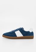 Blauer Wildleder-Sneaker mit niedrigem Schaft, Perforationen, weißem Seitenpaneel und Fersenschlaufe, brauner Gummisohle und Schnürverschluss auf weißem Hintergrund.