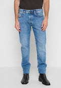 Blaue Denim-Jeans mit geradem Bein, kontrastierenden Nähten, Vorder- und Gesäßtaschen sowie mittelhoher Taille. Getragen mit schwarzen Knöchelstiefeln.