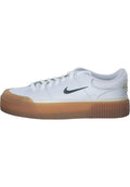 Weiße Sneaker mit einem glatten Lederobermaterial, grauen Schnürsenkeln und einem schwarzen Nike-Swoosh; ausgestattet mit einer tanfarbenen Gummisohle mit einem strukturierten Muster.