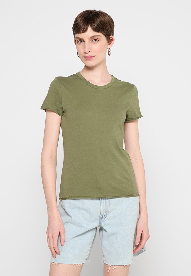 Olivgrünes, tailliertes T-Shirt aus weichem Material, mit Rundhalsausschnitt und kurzen Ärmeln. Kombiniert mit hellblauen Denim-Shorts.