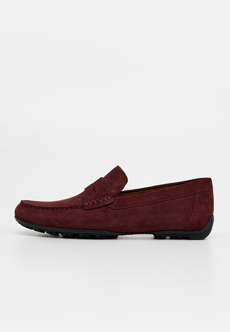 Dunkelroter Wildleder-Herrenslipper mit schwarzer Gummisohle und Mokassin-Nähten auf weißem Hintergrund.
