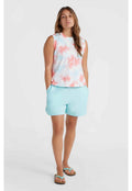 Ärmelloses Batik-Oberteil in Pastellpink, Blau und Weiß; kombiniert mit hellblauen Shorts. Das Modell trägt schwarze Flip-Flops mit türkisfarbenen Riemen.